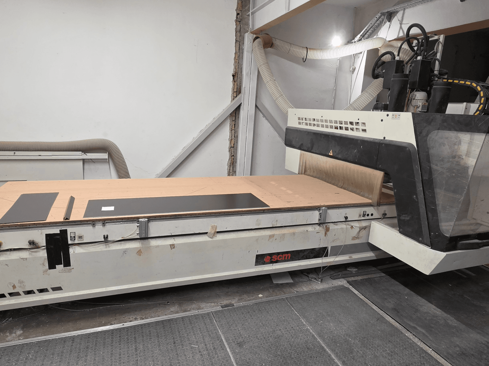 SCM RECORD 132 CNC-bearbetningscenter för trä i sidovy, med ett plant arbetsbord med svarta arbetsstycken och dammuppsamlingssystem.