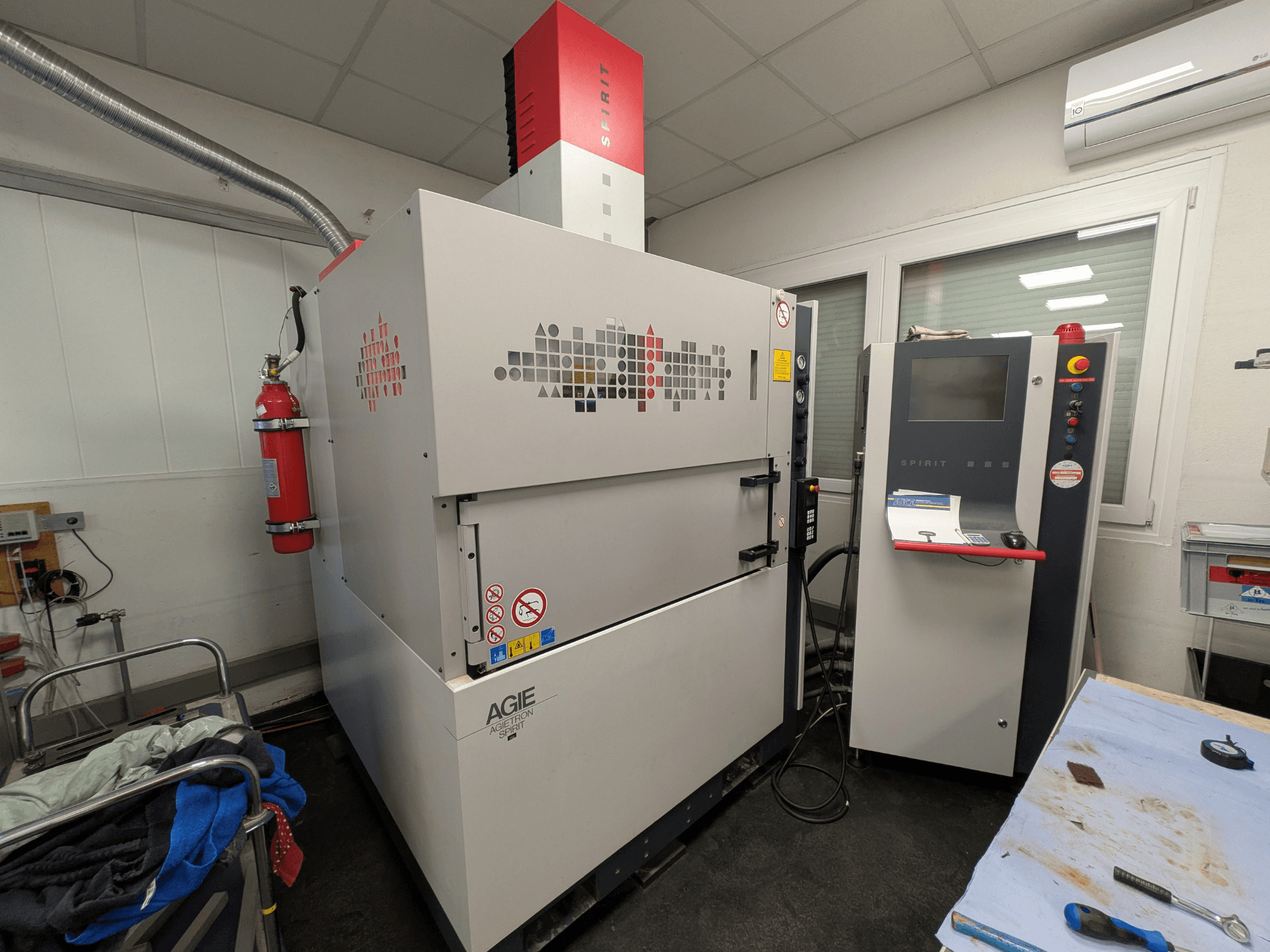 Sänkgnistmaskin AGIE AGIETRON SPIRIT 3, sidovy, visar kontrollpanel och brandsläckare.