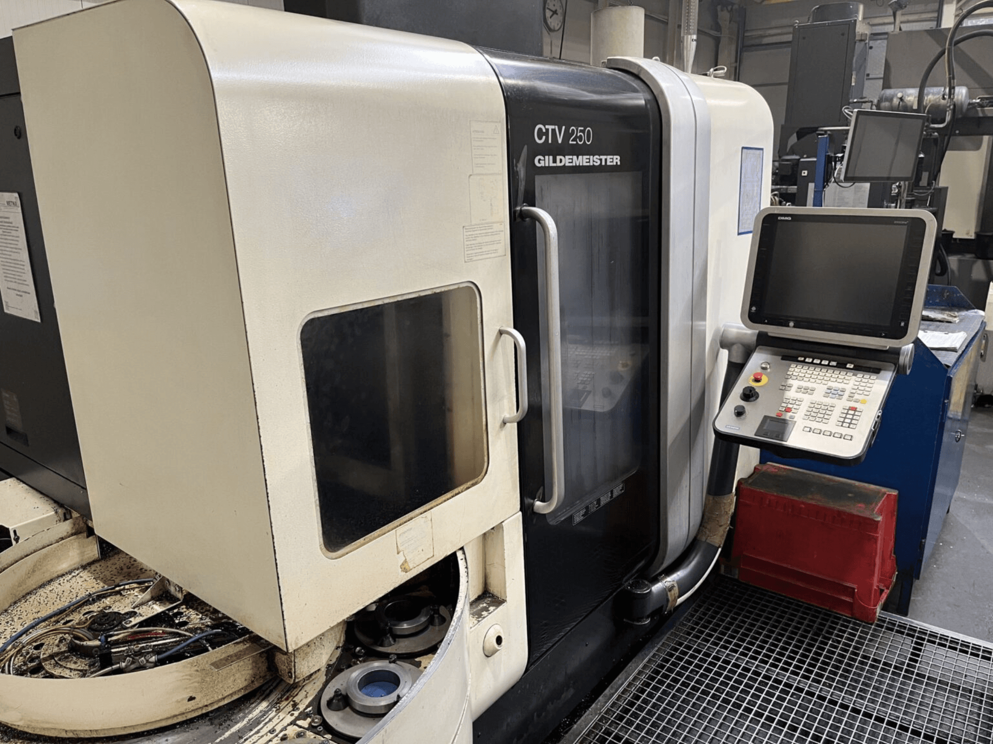 Vertikal svarvmaskin DMG CTV-250 sedd framifrån, med kontrollpanel och arbetsområde med verktyg.