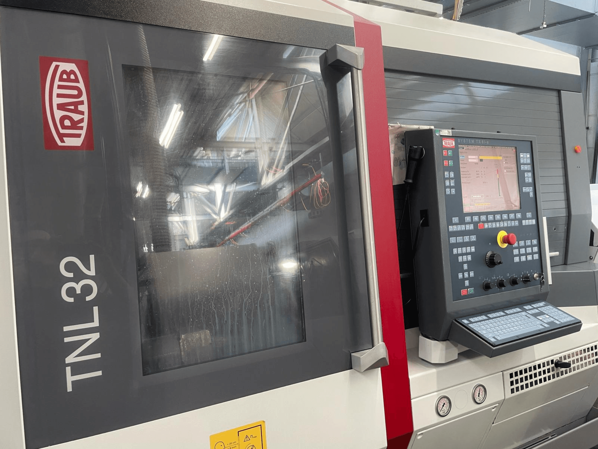 Traub TNL32 CNC-svarv framifrån, med kontrollpanel med knappar, displayskärm och elegant metallhölje.