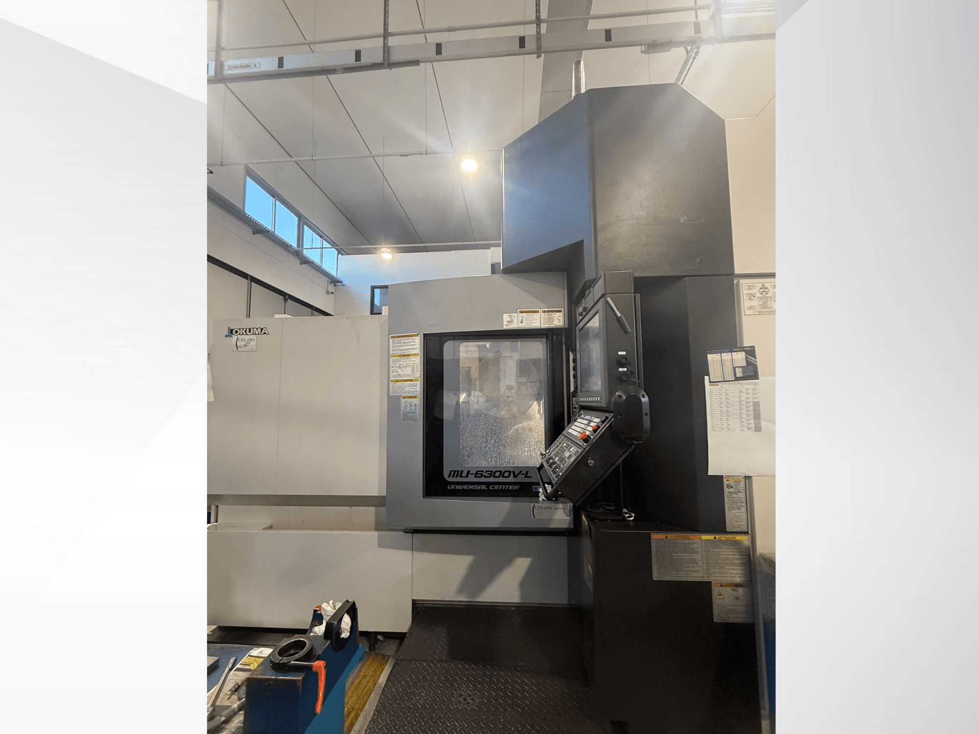 Okuma MU-6300V-L CNC-maskin sedd framifrån, med kontrollpanel och säkerhetsetiketter.