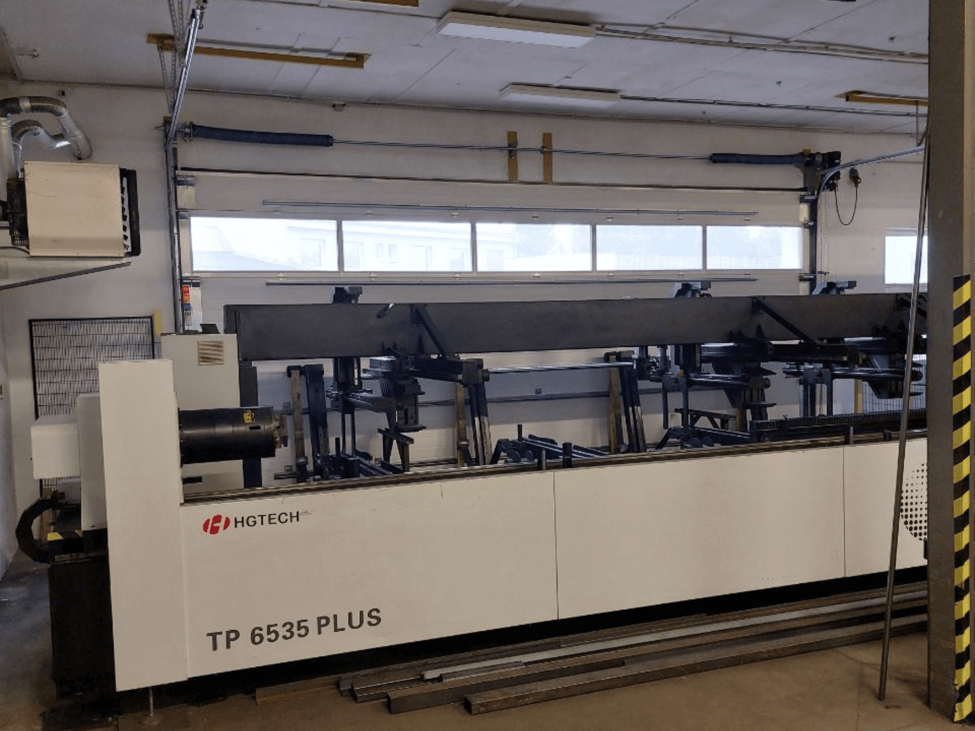 HGTECH TP 6535 PLUS, vy framifrån av en stor industrimaskin med flera armar för precisionstillverkning, placerad i en verkstad.