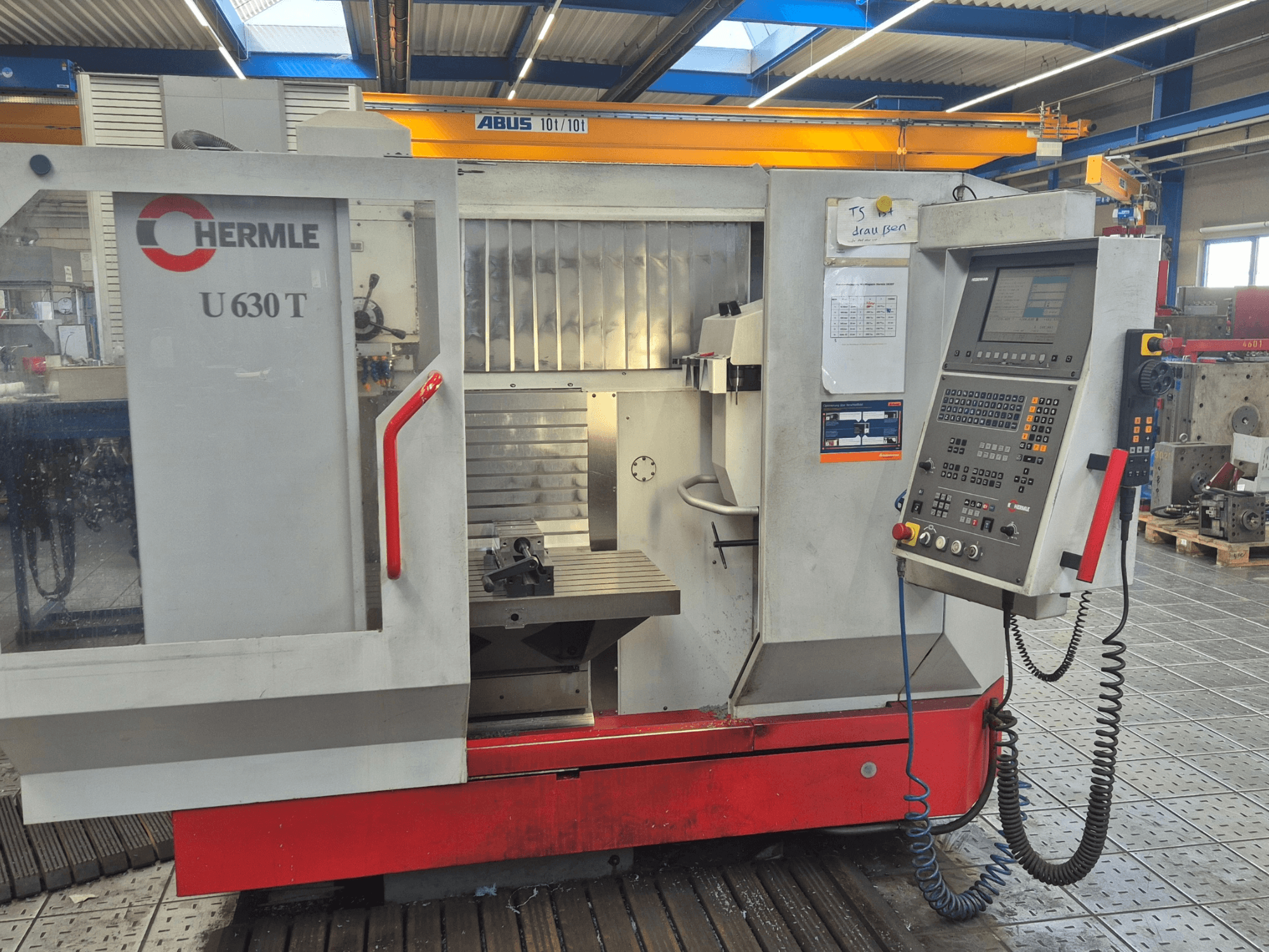 HERMLE U 630 T vertikal fleroperationsmaskin framifrån, med kontrollpanel, arbetsbord och säkerhetsskydd.
