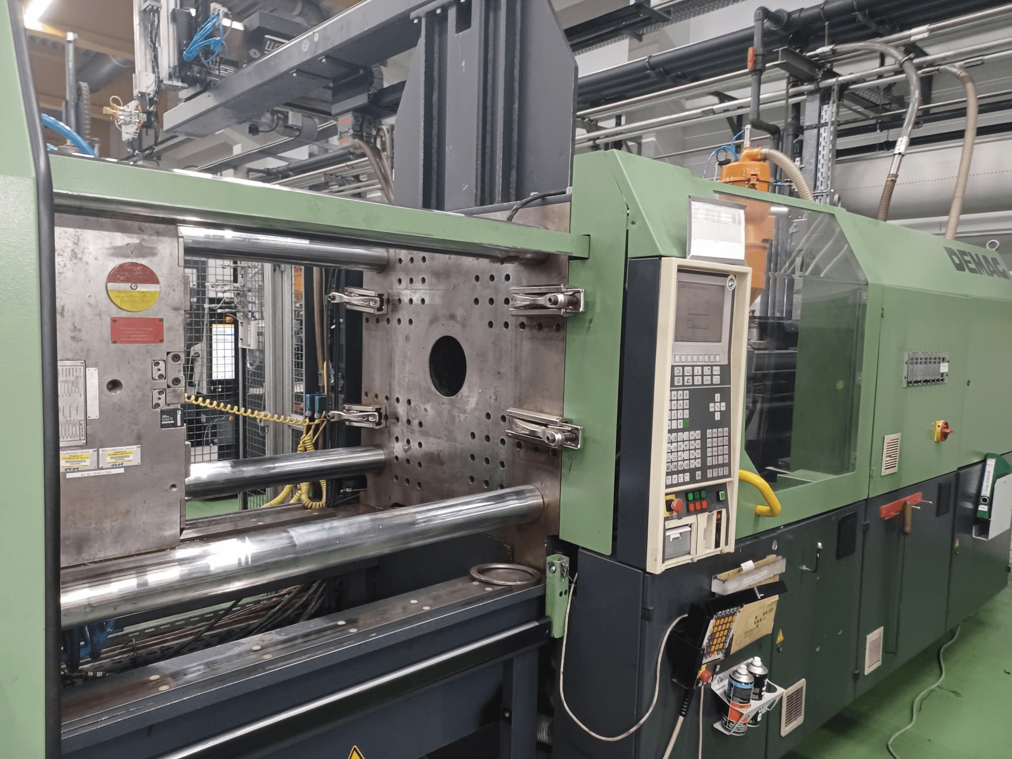 Demag formsprutningsmaskin, framifrån, med kontrollpanel, hydraulcylindrar i metall och säkerhetsfunktioner.