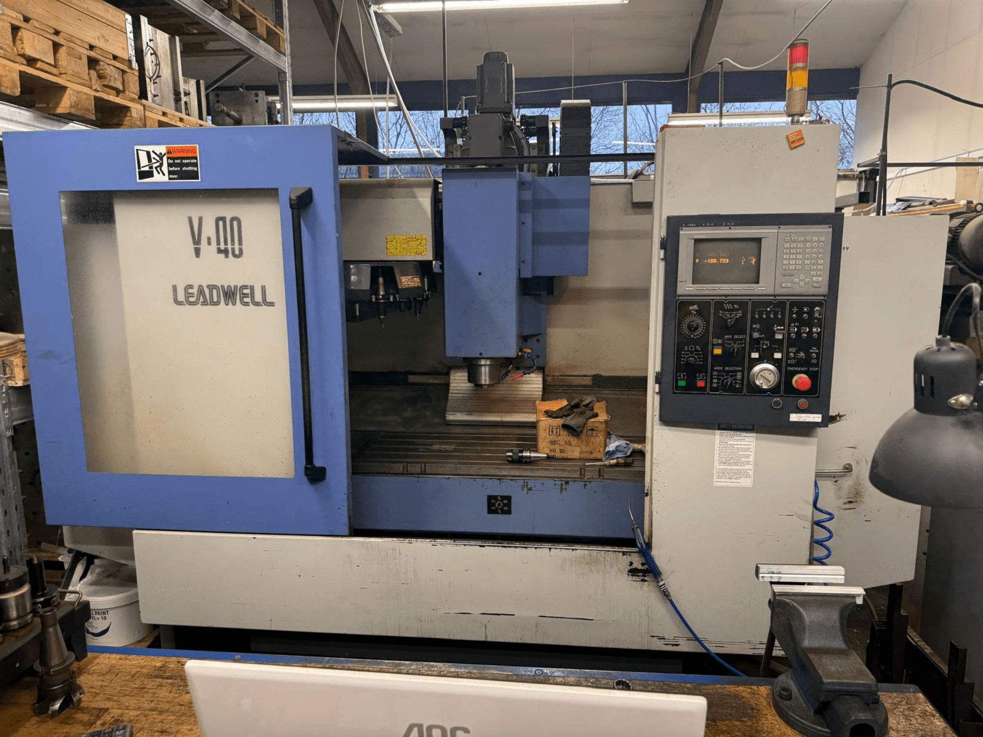 LEADWELL V-40 CNC-fräsmaskin, framifrån, med kontrollpanel, skärverktyg och skruvstäd på en arbetsbänk.