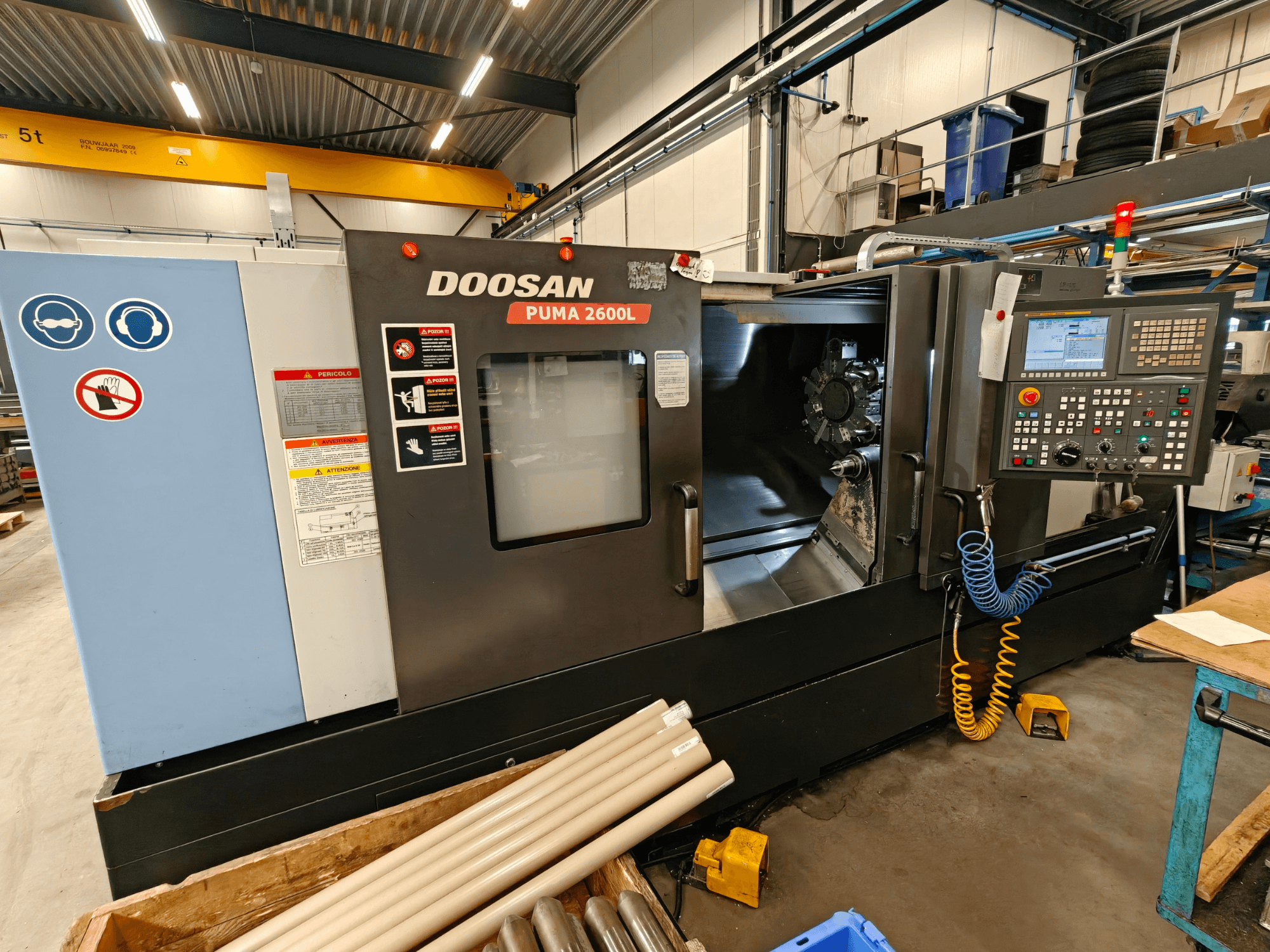DOOSAN Puma 2600L horisontell svarv i en verkstad, sidovy som visar kontrollpanelen och spindelområdet.
