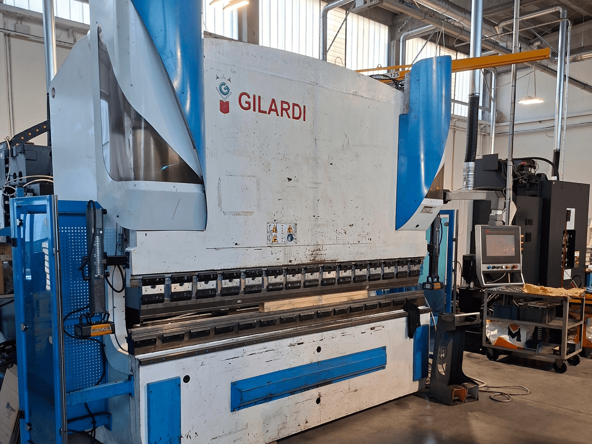 GILARDI Italien 3,25 hydraulisk press, framifrån, med bild på manöverorganen och detaljer från produktionsmiljön.