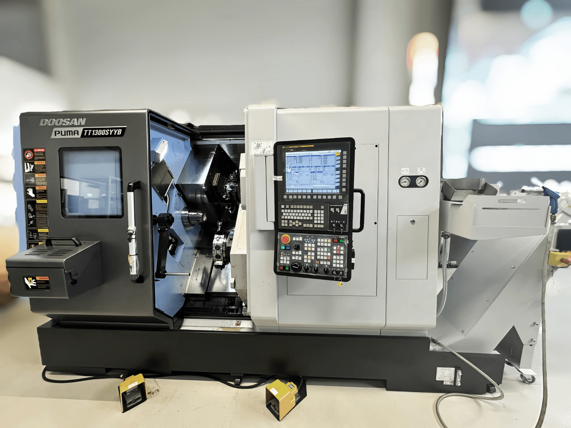 Doosan Puma TT1300SYYB svarv- och fräscenter i sidovy, visar kontrollpanelen och maskinens interiör med synliga verktyg.