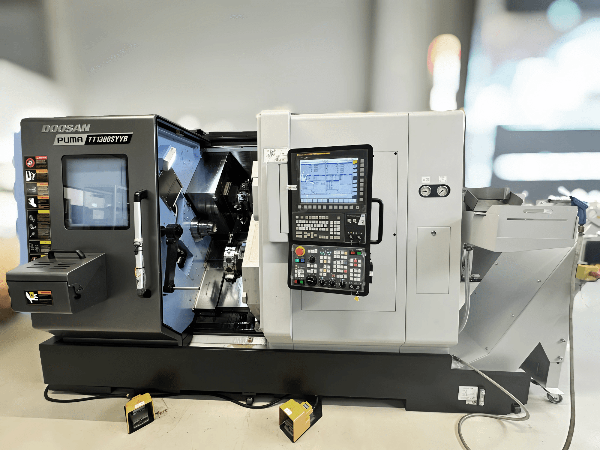 Doosan Puma TT1300SYYB svarv- och fräscenter i sidovy, visar kontrollpanelen och maskinens interiör med synliga verktyg.