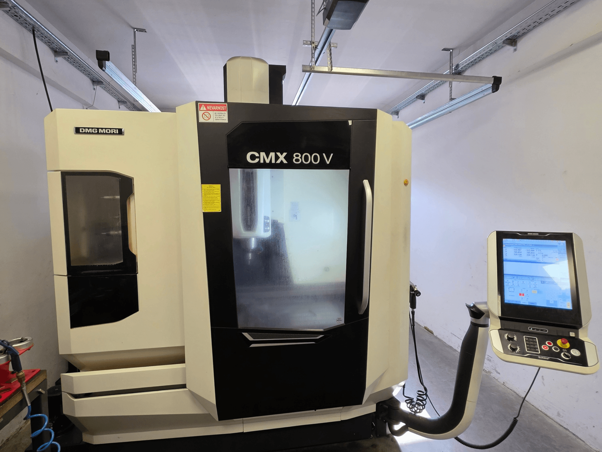 DMG MORI CMX 800V vertikalt bearbetningscenter, framifrån sett, med en pekskärmsbaserad kontrollpanel och tydliga säkerhetsskyltar.