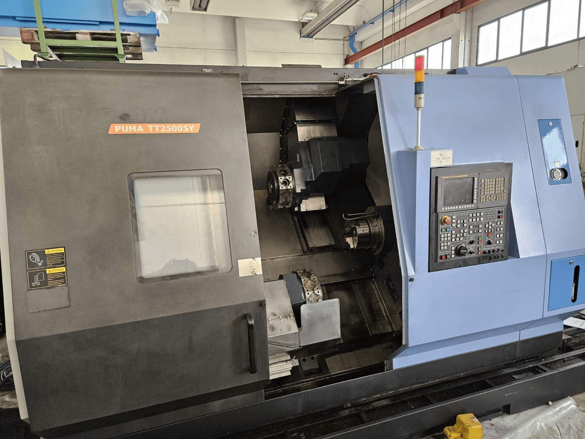 DOOSAN PUMA TT2500SY flerspindlig svarv, framifrån med kontrollpanelen och detaljer från maskinens inre.
