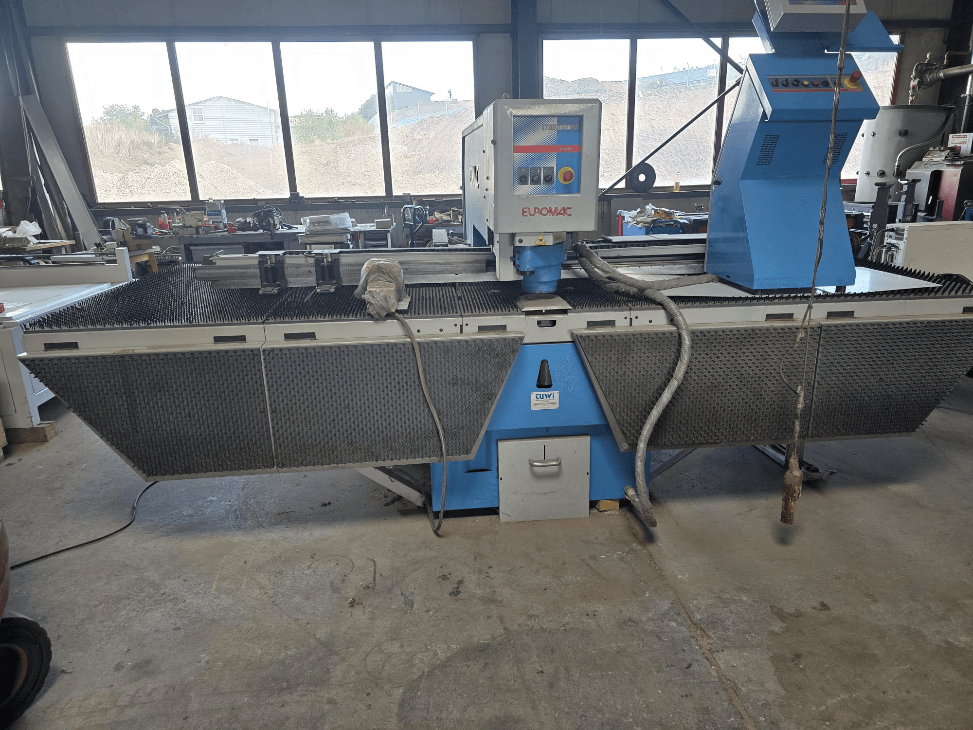 CNC-stansmaskin Euromac BX 1250/30 i en verkstad, sidovy som visar verktygsreglagen, den industriella designen och arbetsbordet för metallbearbetning.
