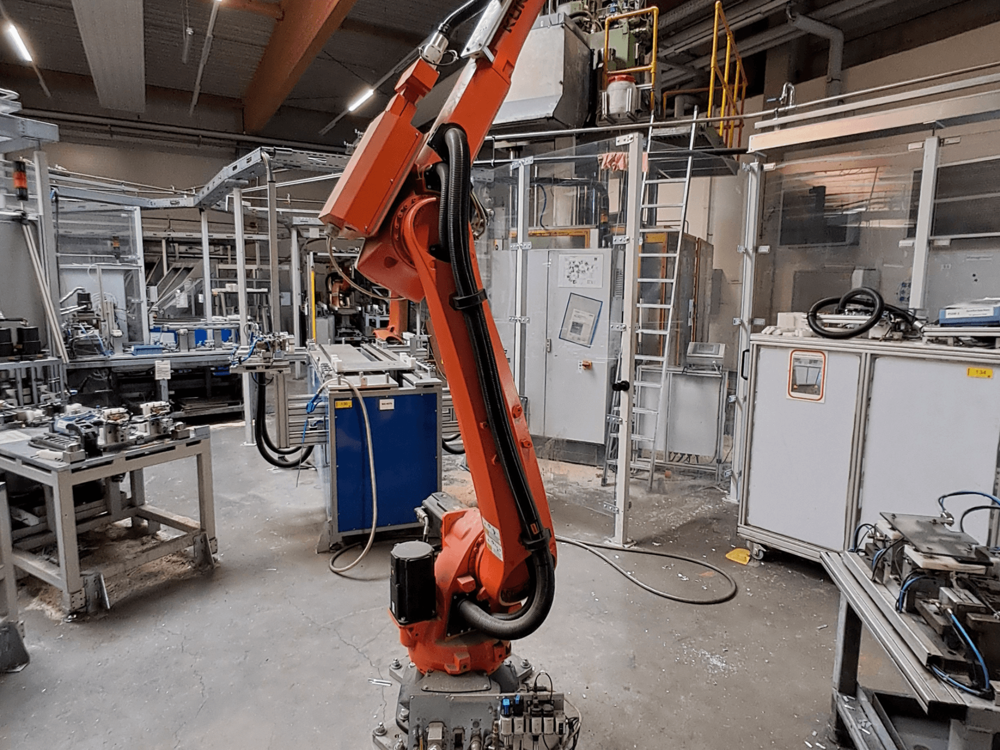 Robotarmen KUKA KR 26 R3100/SEL i en industriell miljö, visad i sidovy med driftsutrustning i bakgrunden.