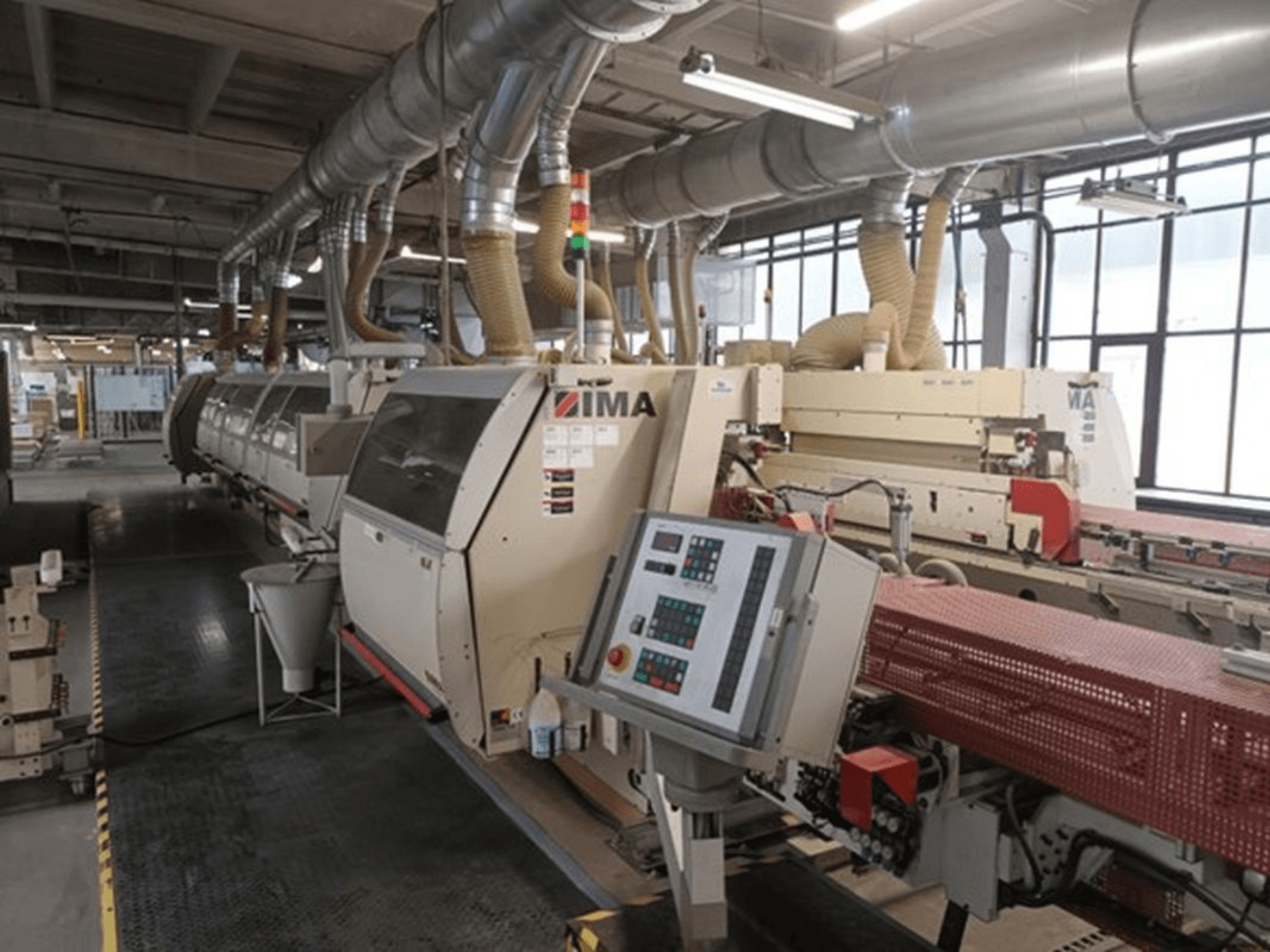 IMA industrimaskiner i en fabriksmiljö, framifrån, med kontrollpaneler och dammutsugningsrör.