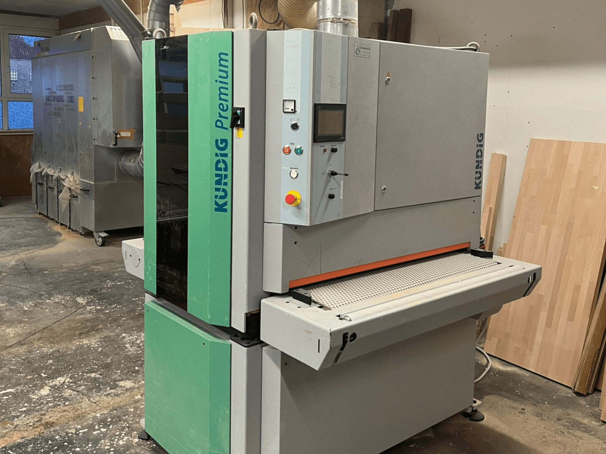 Kundig Premium-1 1100K bandslip i grått och grönt, visad i sidovy med kontrollpanelen och slipbandet synliga.