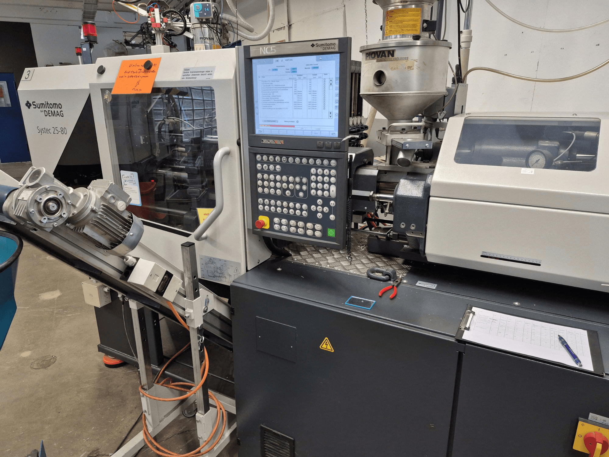 Hydraulisk formsprutningsmaskin SUMITOMO SHI DEMAG Systec 25/320-80, framifrån sett med kontrollpanel och matningssystem synliga.
