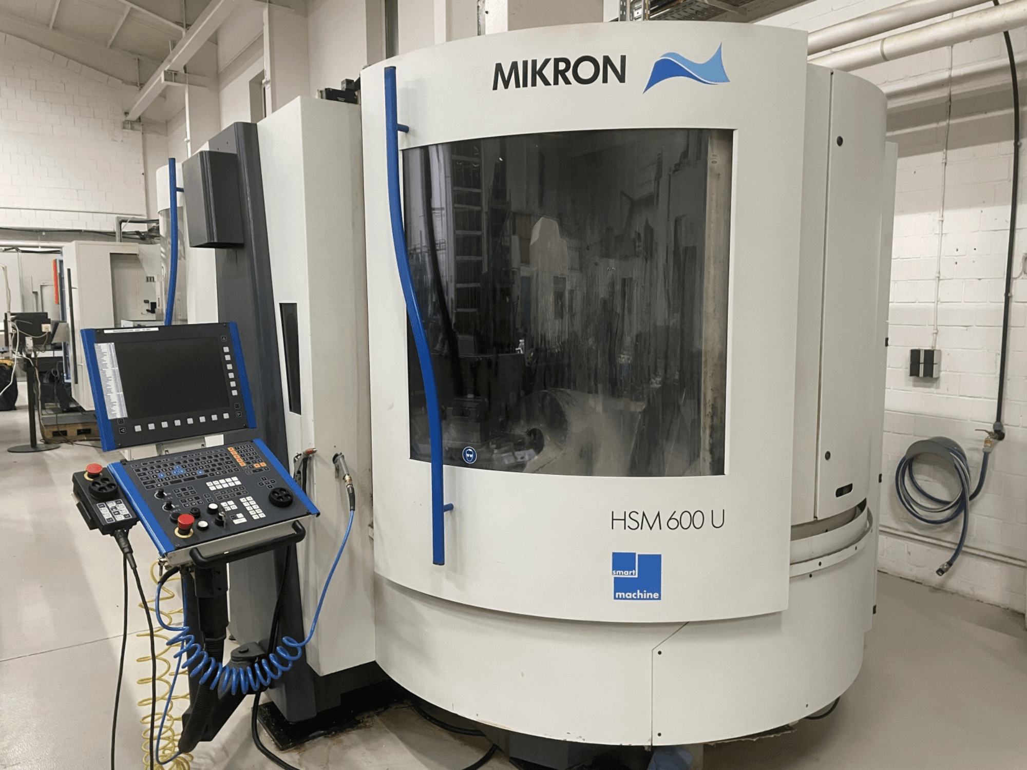 MIKRON HSM600U vertikal fleroperationsmaskin visad framifrån, med en operativ kontrollpanel och ett stort visningsfönster.