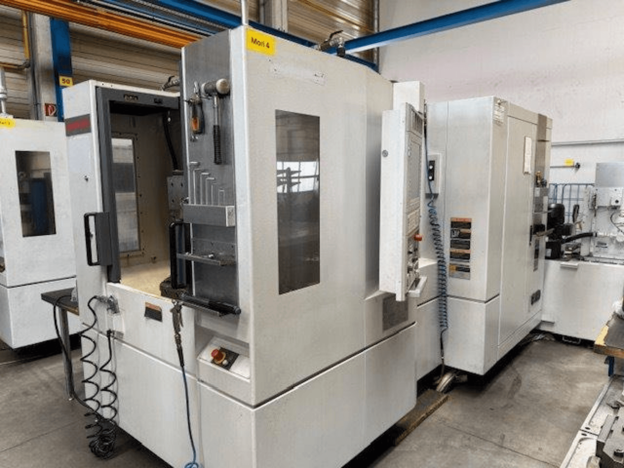MORI SEIKI NH4000 DCG horisontell fleroperationsmaskin visad framifrån, med öppen dörr och detaljer på kontrollpanelen.