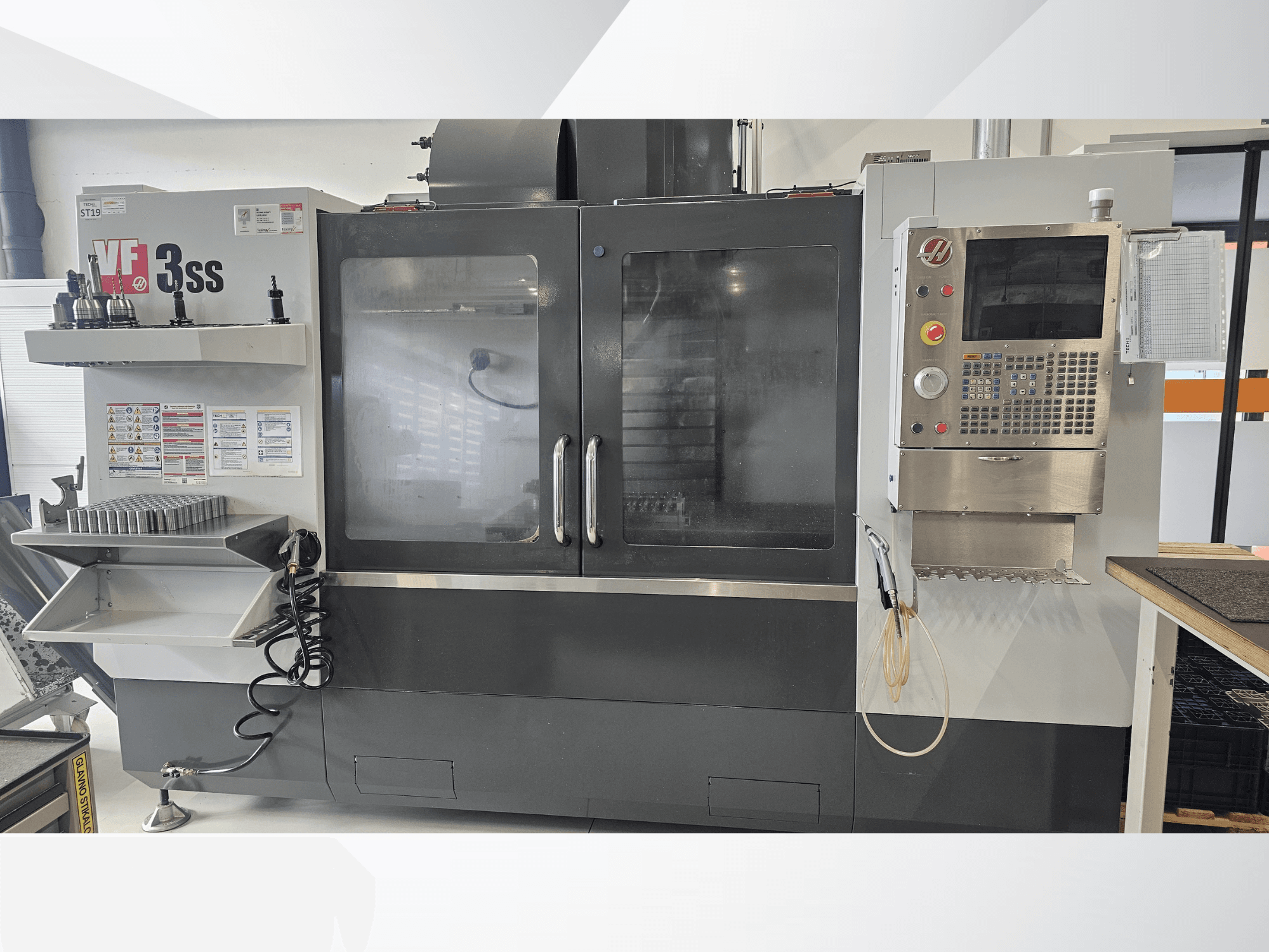 HAAS VF-3SS vertikalt bearbetningscenter, framifrån, med kontrollpanel, verktygshylla och stor glasdörr.