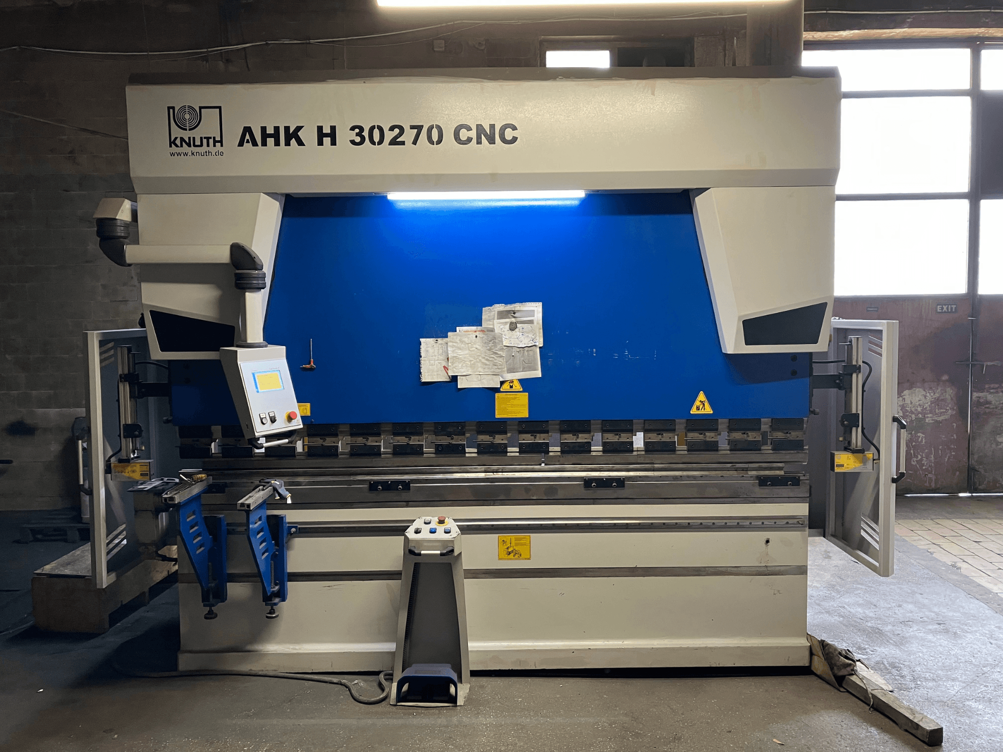 KNUTH AHK H 30270 CNC-kantpress i en verkstad, framifrån, där man ser kontrollpanelen och den blå-vita designen, med öppen sidodörr.