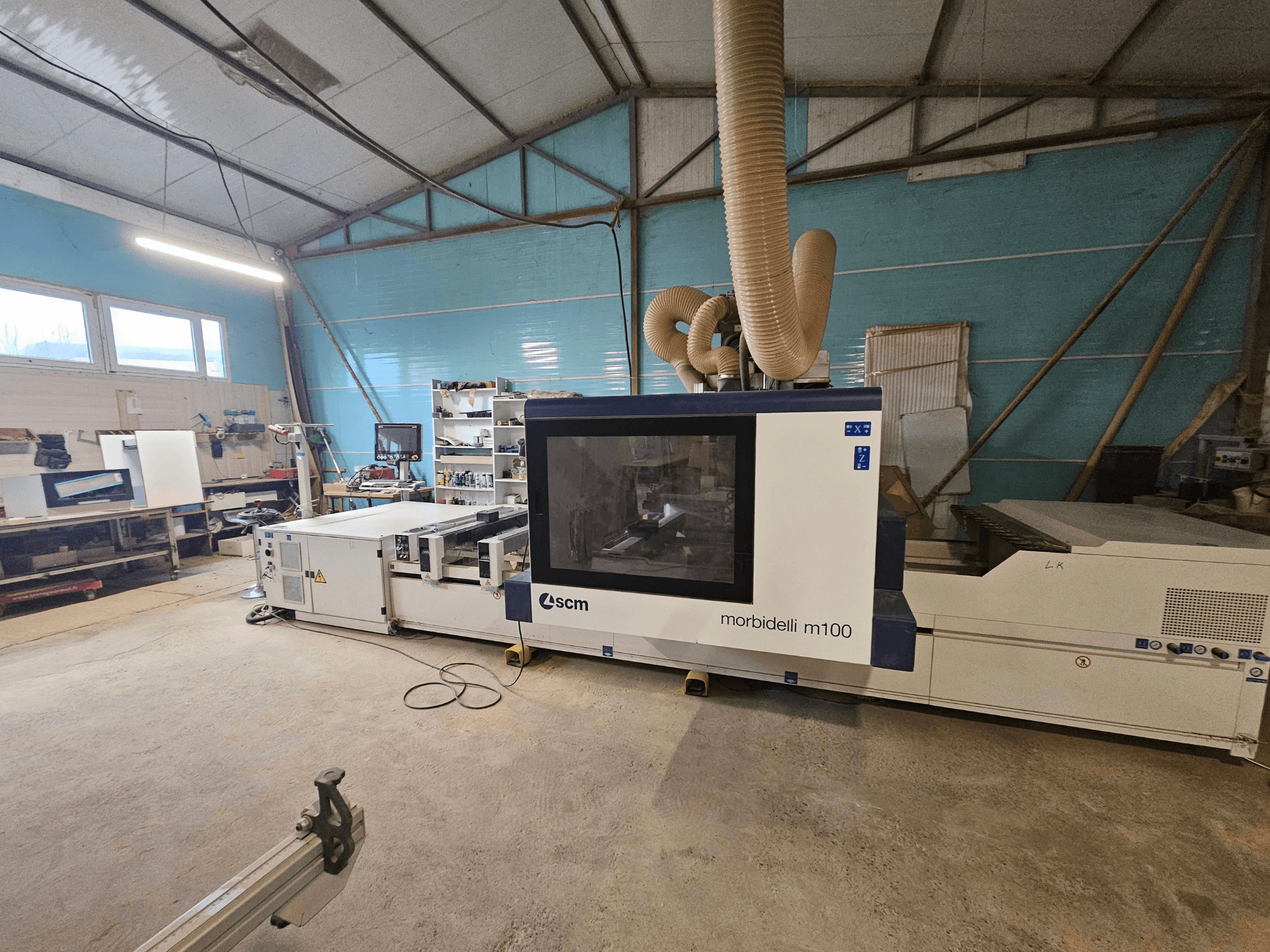 SCM Morbidelli M100 CNC-maskin i en verkstad, framifrån, med dammutsugningssystem och kontrollpanel.