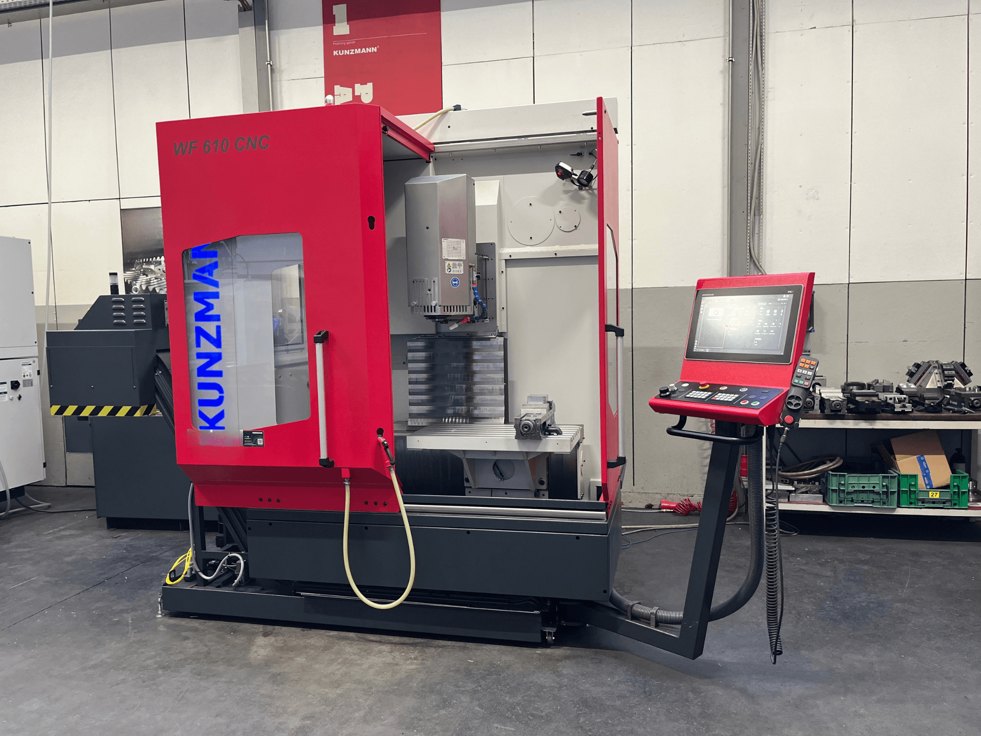 Ett vertikalt CNC-bearbetningscenter av typen KUNZMANN WF 610 i en verkstad, med kontrollpanel och synliga maskinkomponenter.