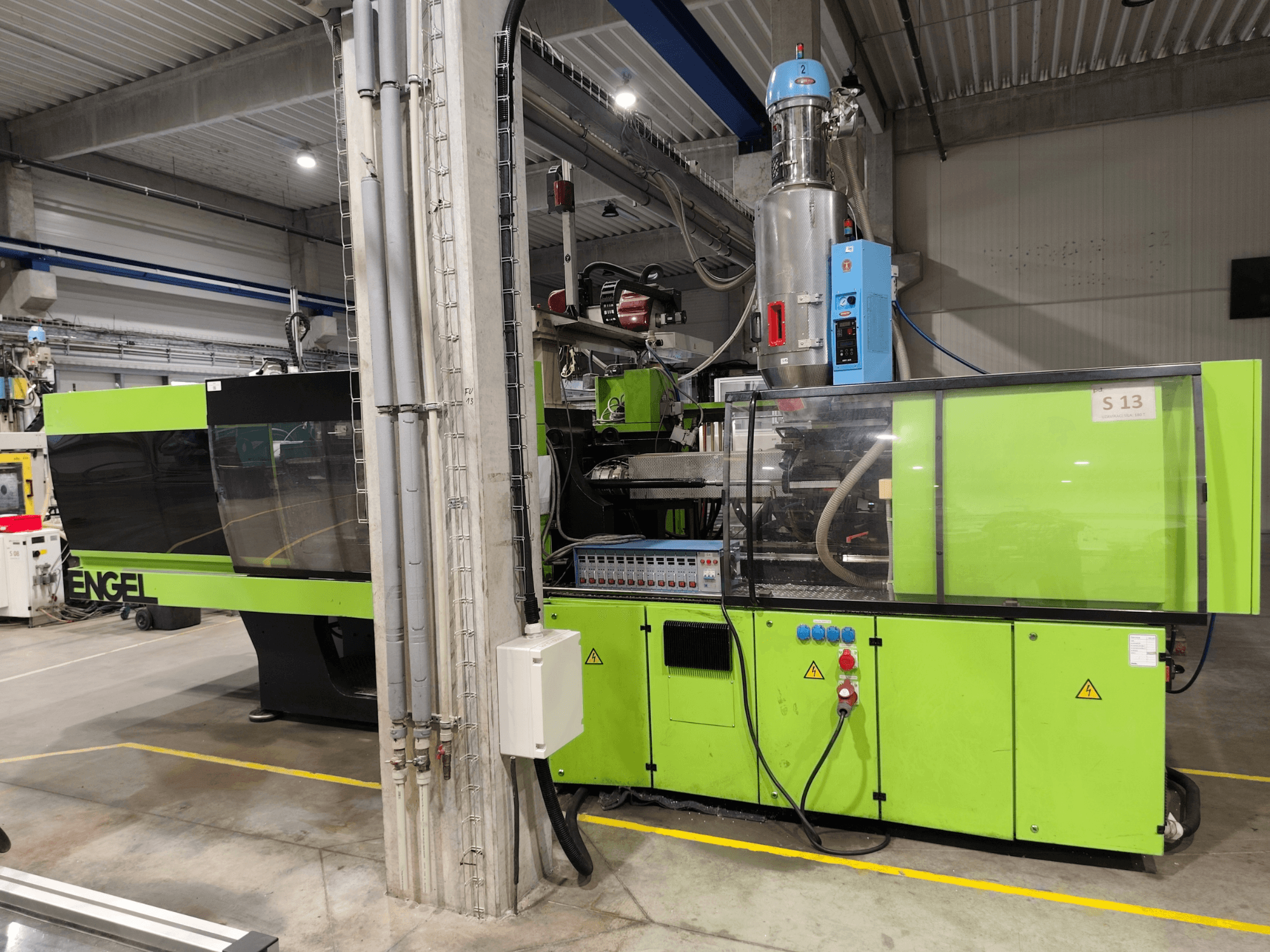 Hydraulisk formsprutningsmaskin av typen Engel Victory 750/180, framifrån, med grön yttre färg och detaljer på kontrollpanelen.