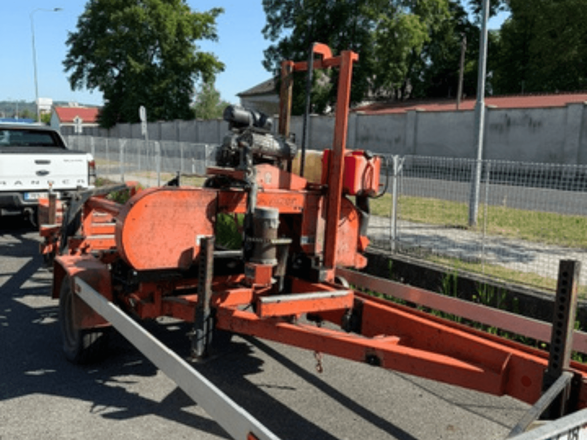 WOOD-MIZER LT40 bandsåg för trä i orange, sidovy på en släpvagn med synliga hjul och motorkomponenter.