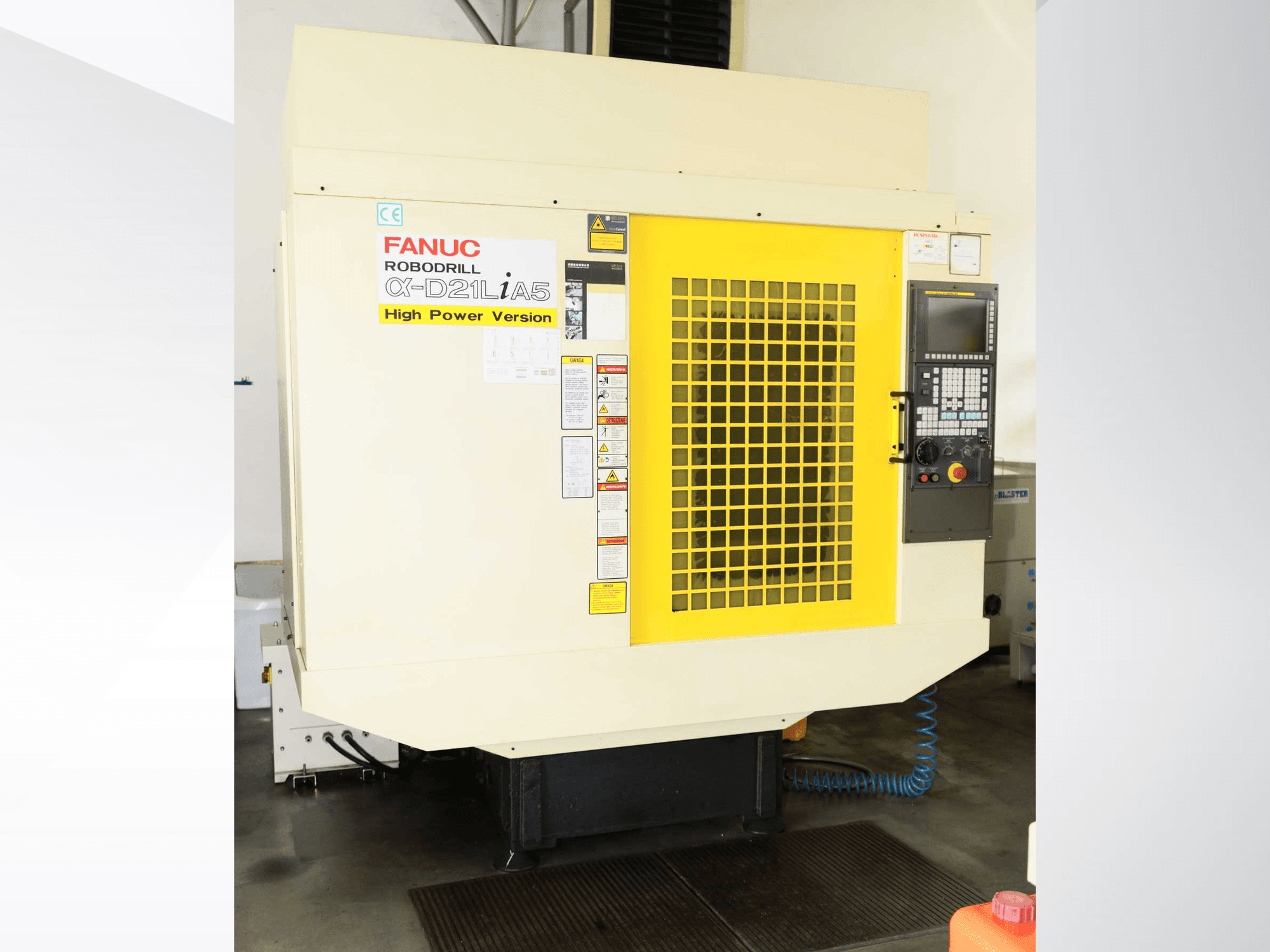 FANUC ROBODRILL α-D21LiA5 vertikalt bearbetningscenter, framifrån sett med gult säkerhetsgaller och detaljer på kontrollpanelen.