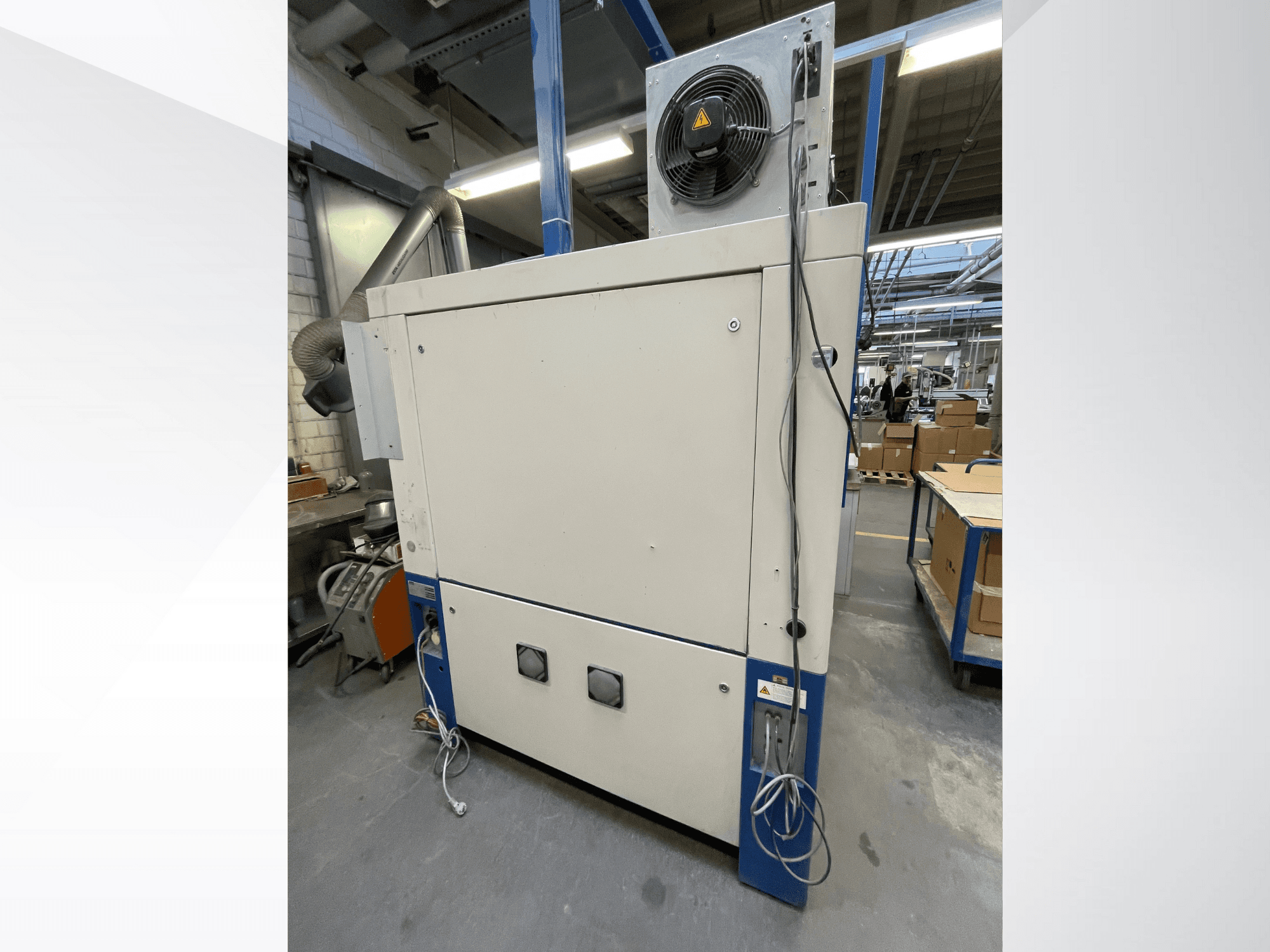 Industriell torkmaskin med fläkt, vy från sidan; har ventilation och flera elektriska anslutningar. Märke/modell ej synlig.