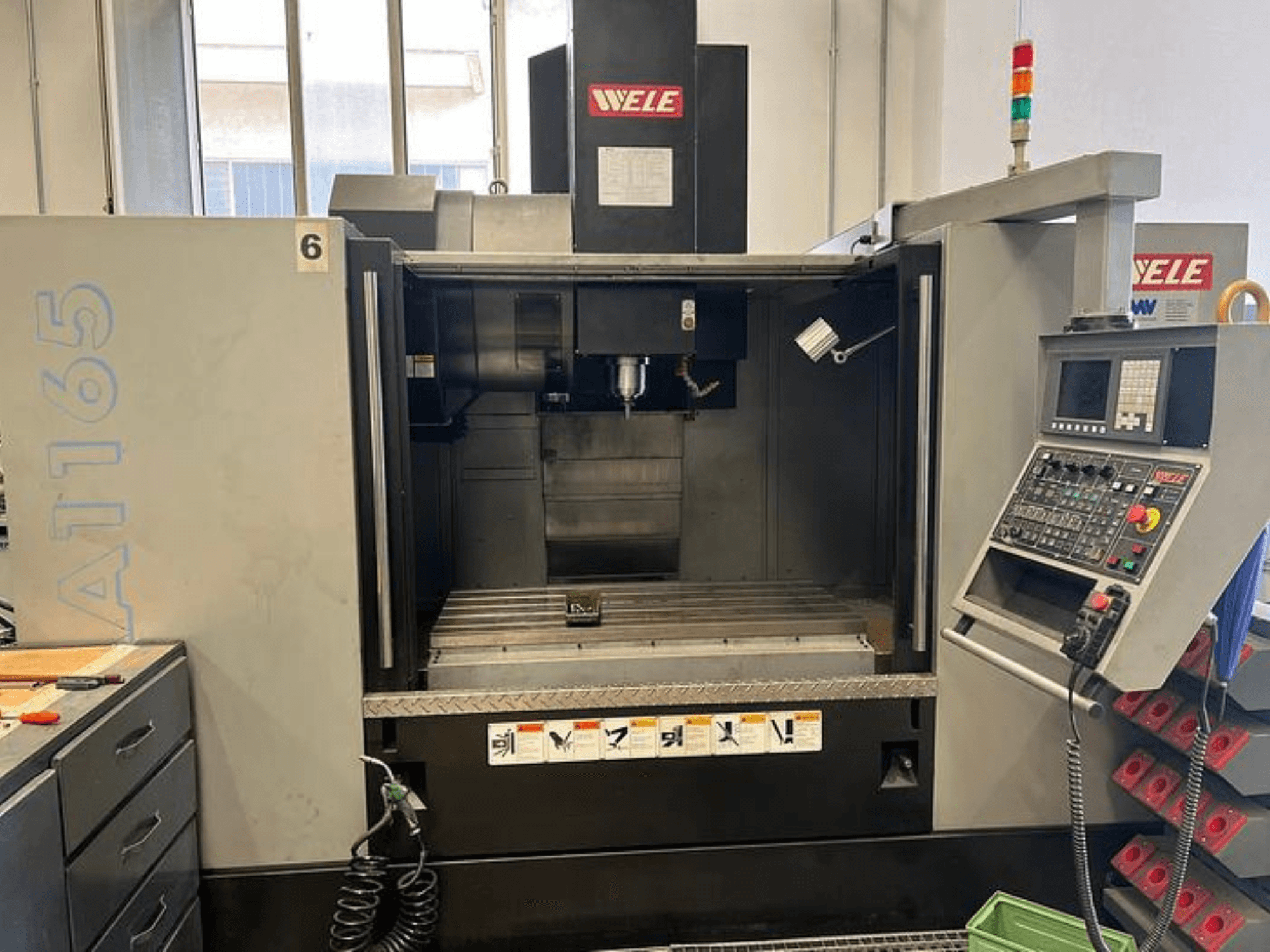 WELE A165 CNC-bearbetningscenter, framifrån, med kontrollpanel, verktygshållare och arbetsbord synliga. Industriell miljö.