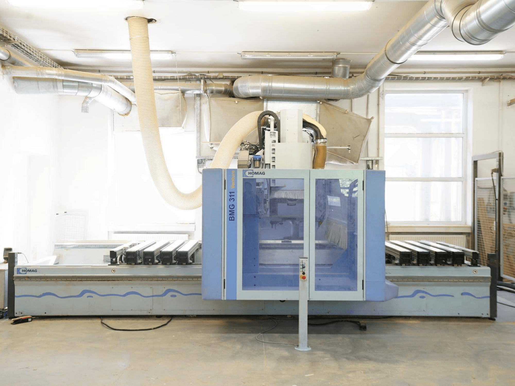 CNC-träbearbetningscenter HOMAG V BMG 311/42/F/K, framifrån, med stort arbetsbord och dammutsugssystem.