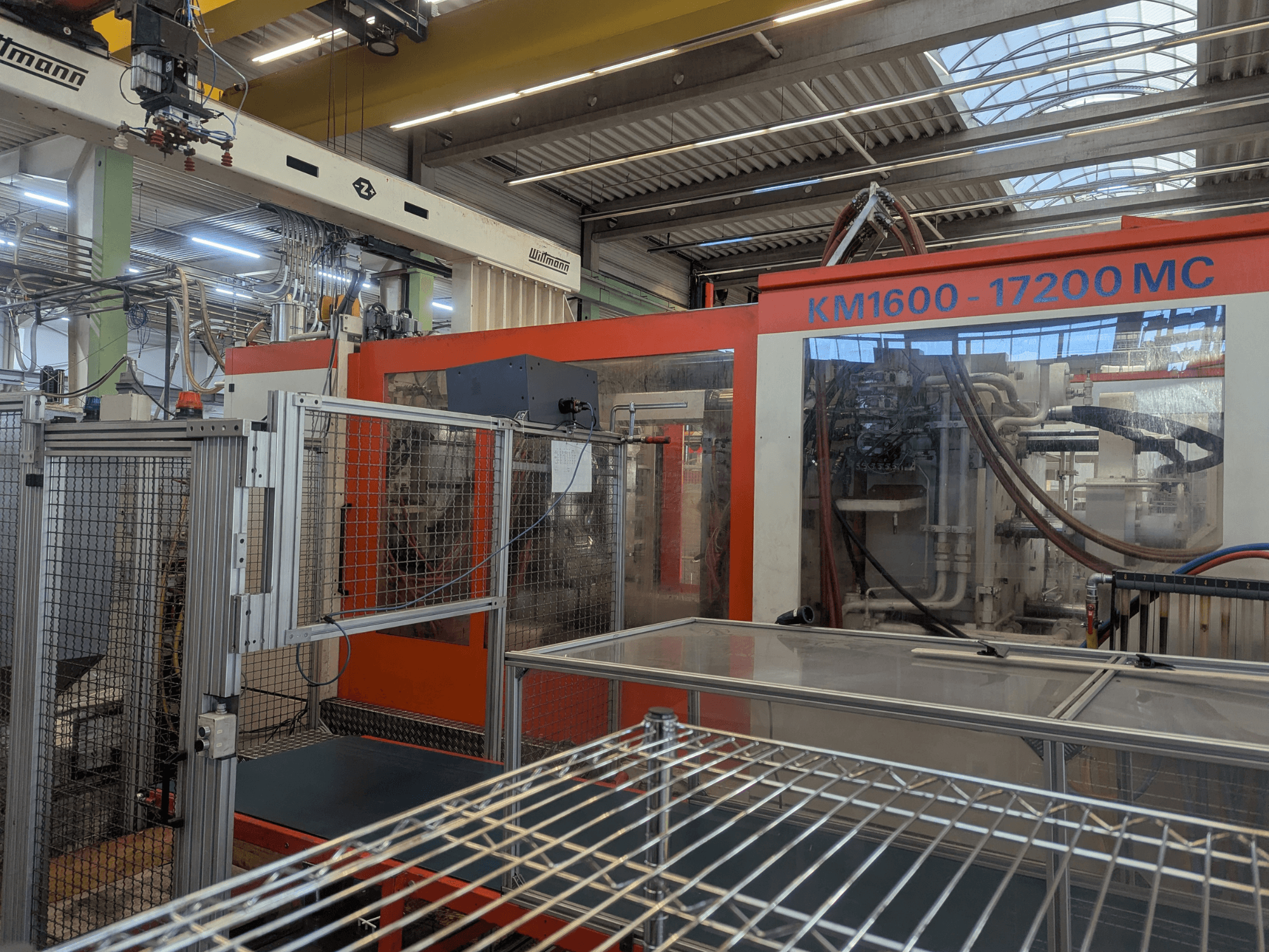 Hydraulisk formsprutningsmaskin Krauss Maffei KM 1600-17200MC, framifrån med synlig kontrollpanel och hydraulledningar.