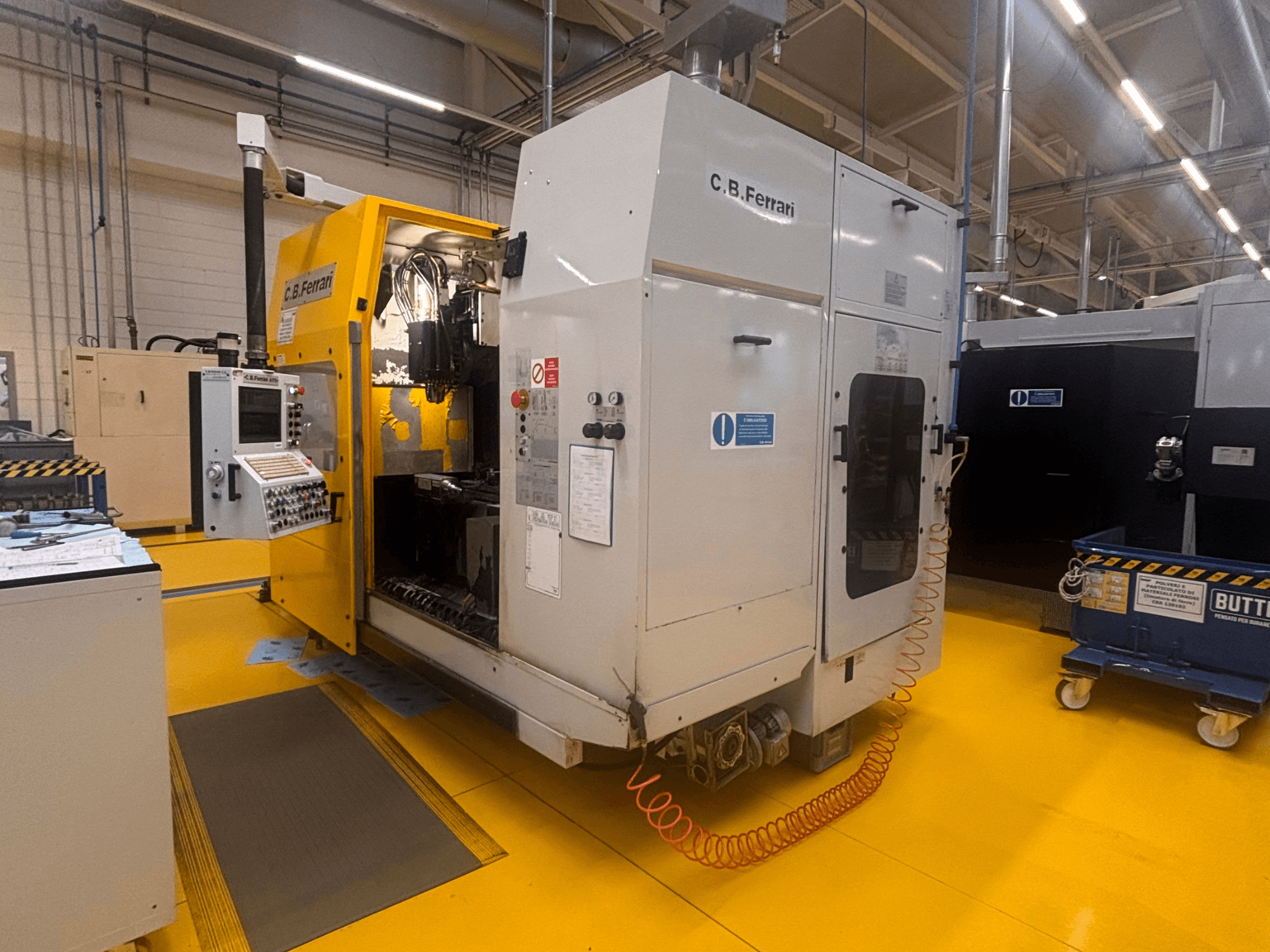 C.B. Ferrari A175 vertikal fleroperationsmaskin i fabriksmiljö, framifrån med kontrollpanelen och den öppna luckan synliga.