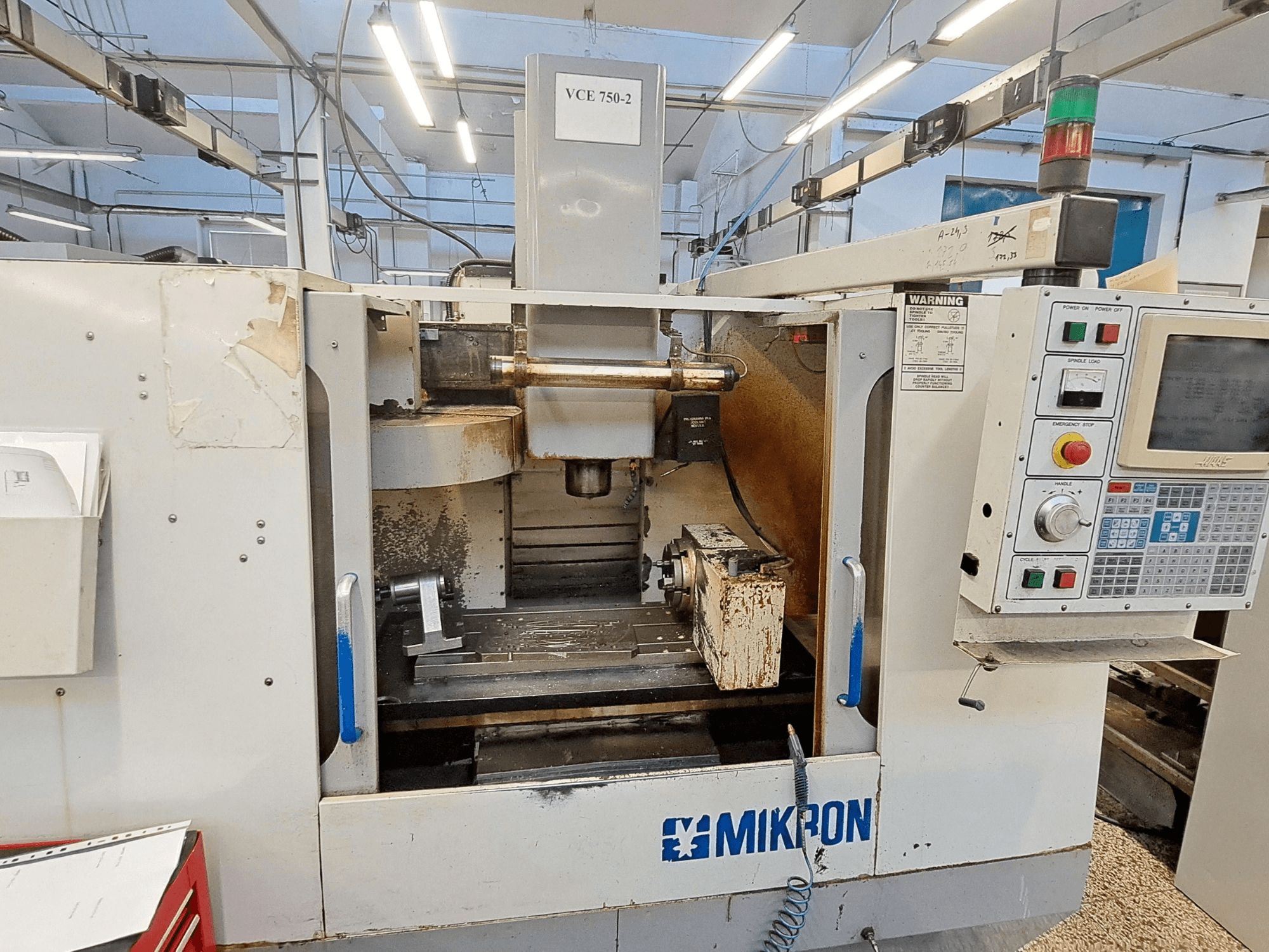 Mikron VCE 750-2 CNC-fräsmaskin, vy framifrån, med kontrollpanel och spindel i bearbetningsområdet, visar slitage och smuts.