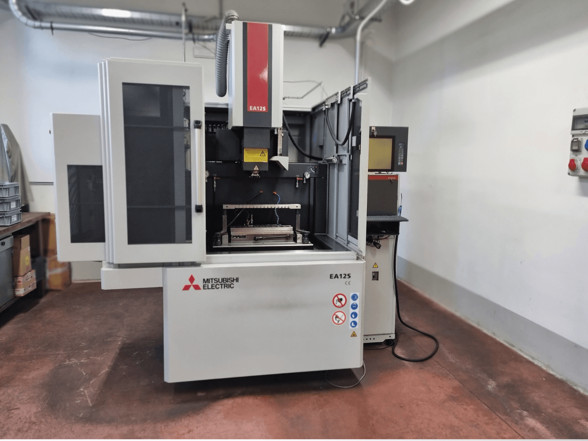 Mitsubishi Electric EA12S trådskärmaskin, framifrån, med öppna dörrar, kontrollpanel och säkerhetsetiketter.