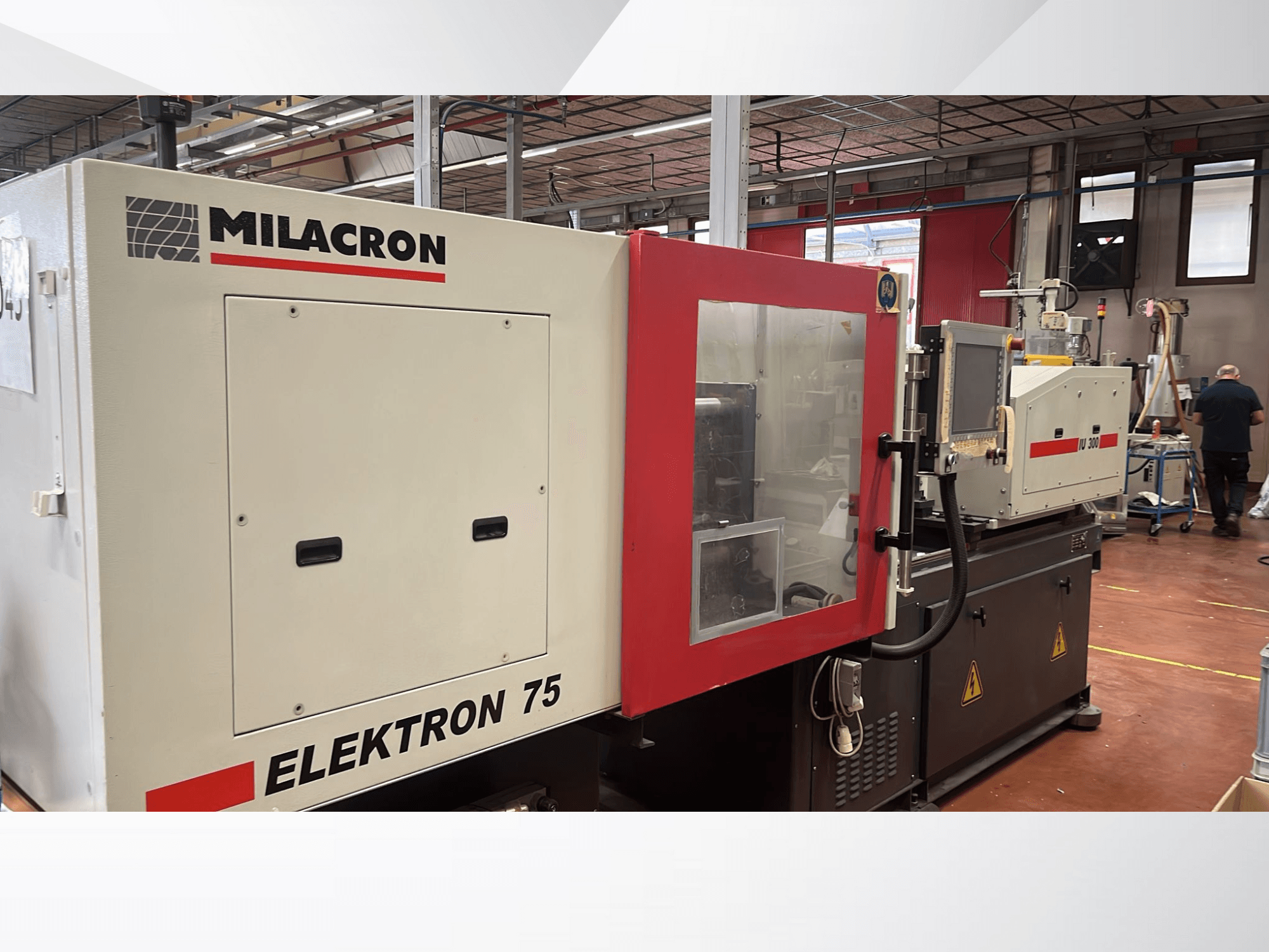 Milacron Elektron 75 formsprutningsmaskin i verkstadsmiljö, sidovy som visar kontrollpanelen och de mekaniska delarna.