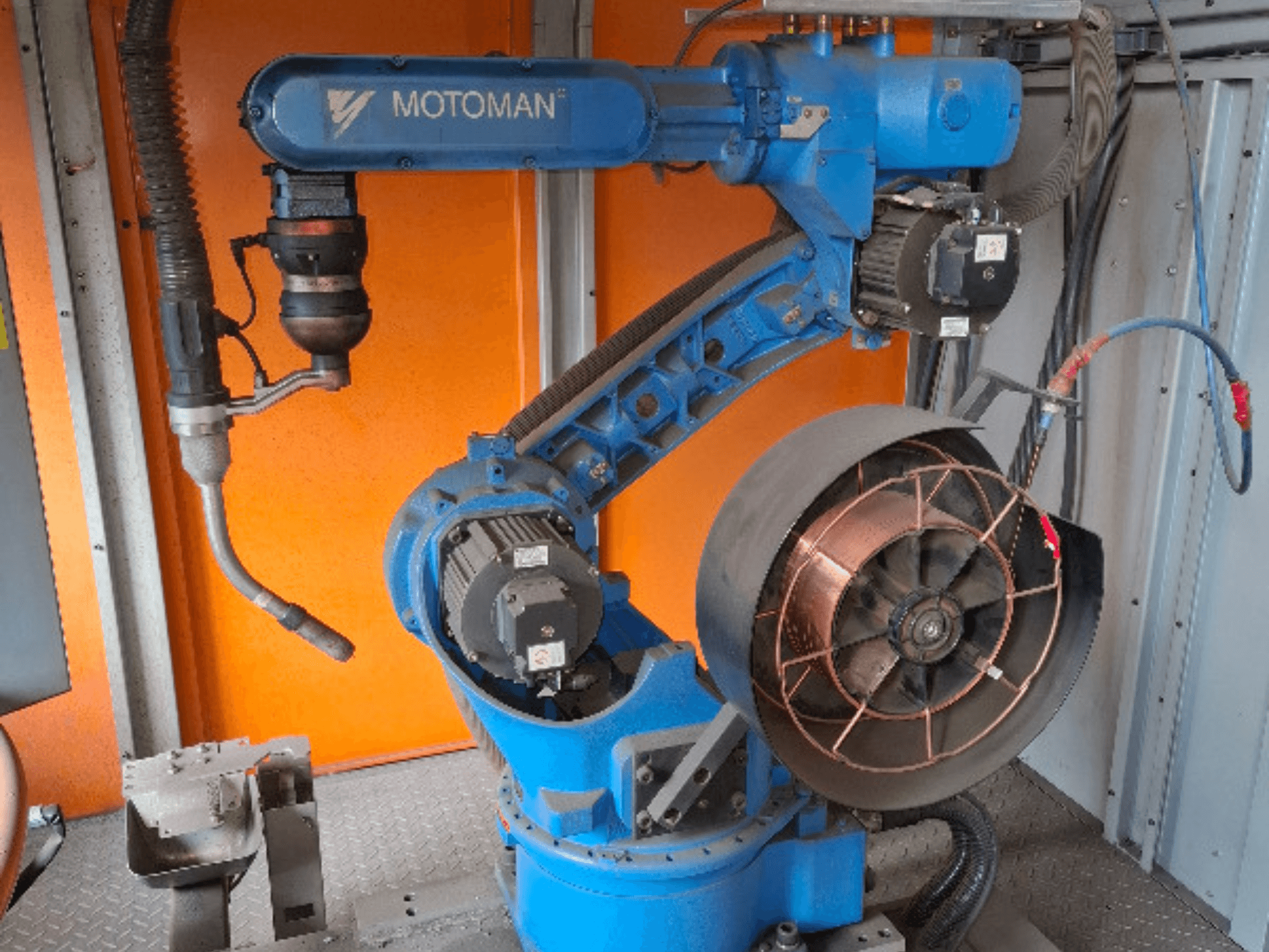 MOTOMAN robotarm i blått, vy från sidan, med påmonterad fläkt och verktyg, visar mekaniska detaljer och anslutningar.