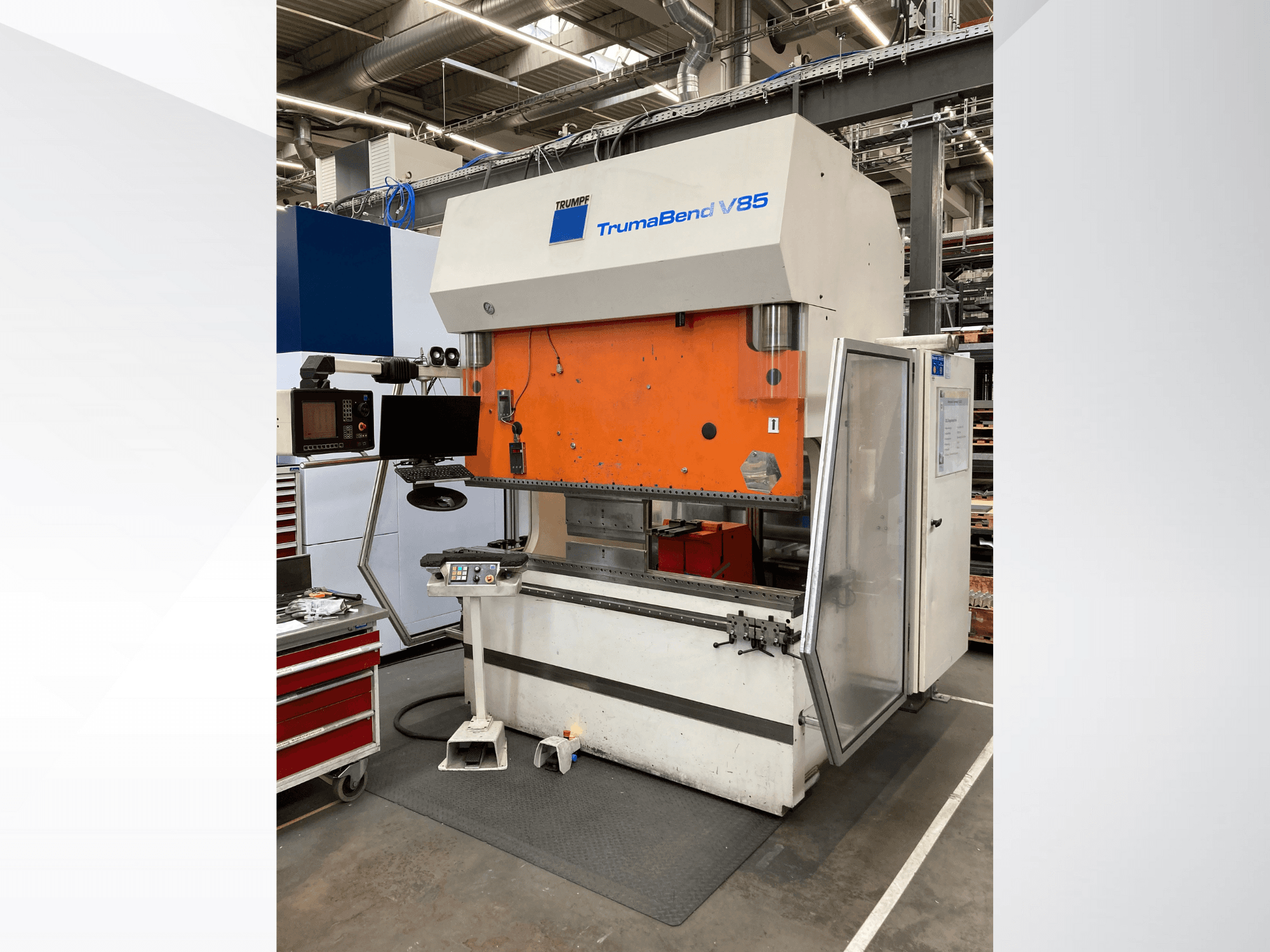 TruMatic V85 bockningsmaskin i en fabrik, med orange frontpanel, kontrollskärm och öppen sidodörr, vy från sidan.