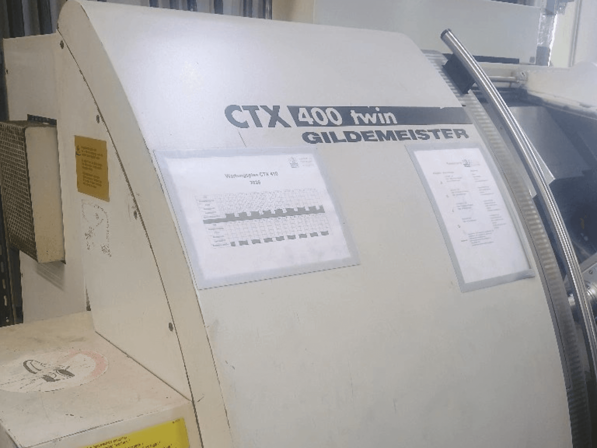 Gildemeister CTX 400 dubbel horisontell svarv, framifrån, med kontrollpaneler och teknisk dokumentation.