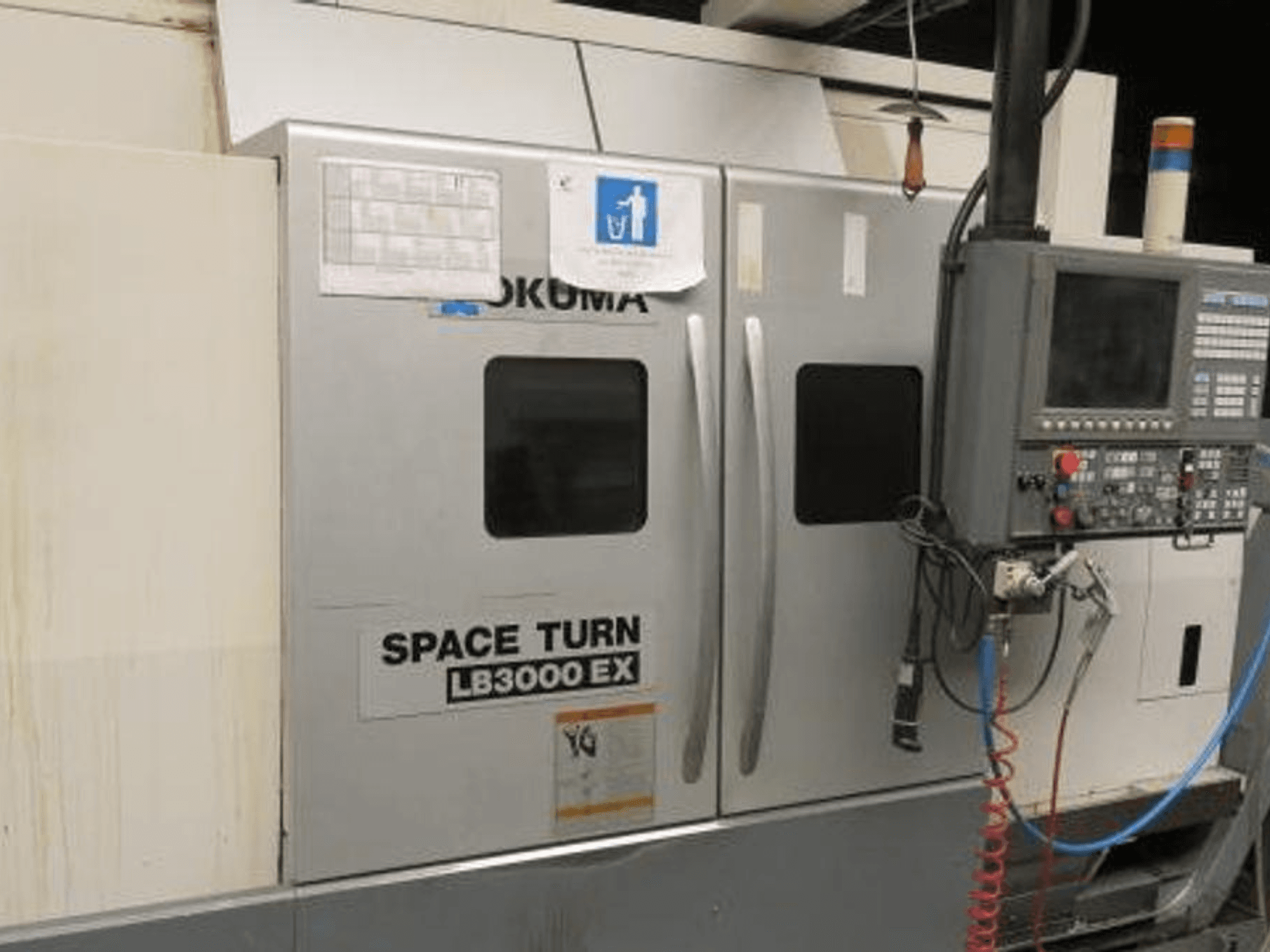 Okuma Space Turn LB3000 EX CNC-svarv, sidovy, med kontrollpanel, två dörrar och synlig kabeldragning.